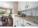Close-up of a modern kitchen featuring white cabinets, granite countertops, and views into the dining room at 145 Basket Grass Ln, Summerville, SC 29486