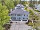 Aerial view of a blue house with a three-car garage nestled among lush green trees at 1531 Capel St, Mount Pleasant, SC 29466