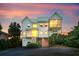 Exterior view of beautiful home with sunset skies and meticulously landscaped yard at 1676 E Ashley Ave, Folly Beach, SC 29439
