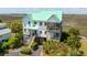 Attractive three-story beach home featuring a green metal roof, screened porch, and lush landscaping at 1676 E Ashley Ave, Folly Beach, SC 29439