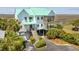 Inviting two-story home with a charming red door, covered porch, lush landscaping, and ample parking at 1676 E Ashley Ave, Folly Beach, SC 29439