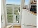 Upstairs view of backyard pier through large windows from the stairwell with wood flooring and railing at 1676 E Ashley Ave, Folly Beach, SC 29439