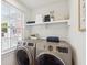 Well-lit laundry room with modern washer and dryer and open shelf at 22 Sheppard St, Charleston, SC 29403