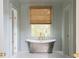Luxurious bathroom with soaking tub, brass fixtures, paneled walls, and natural light from the window at 2407 Atlantic Ave, Sullivans Island, SC 29482