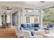 Inviting screened patio features comfortable seating with blue cushions and a dining area with ceiling fans at 2407 Atlantic Ave, Sullivans Island, SC 29482