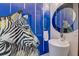 Unique powder room with zebra art, vessel sink, and round mirror with blue accent wall at 2732 Canebreak Ln, Mount Pleasant, SC 29466