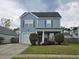 Charming two-story home with light-blue siding, a well-manicured lawn, and a driveway leading to an attached garage at 328 Bradley Bend Dr, Moncks Corner, SC 29461