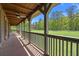 Covered porch with wooden flooring and railings, offering scenic views of the surrounding greenery at 3936 Lodge Hwy, Smoaks, SC 29481