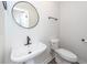 Bright powder room featuring a pedestal sink, round mirror, and modern black fixtures at 521 Savannah Rd, Ladson, SC 29456