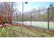 Fenced tennis court offers a recreational amenity, lit for night play and surrounded by mature trees at 5400 Rock Creek Ct, North Charleston, SC 29420