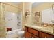 Bright bathroom with granite counters, a cherry vanity, tub/shower combo, and decorative shelving at 559 Eastern Isle Ave, Summerville, SC 29486
