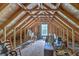 Spacious unfinished attic area featuring exposed wooden beams and a window at 5950 Lowell Reed Rd, Ravenel, SC 29470