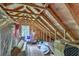 Unfinished attic space featuring exposed wooden beams, plywood walls, and a window at 5950 Lowell Reed Rd, Ravenel, SC 29470