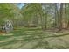 Expansive backyard with lush green grass, mature trees, and partial views of the house and porch at 5950 Lowell Reed Rd, Ravenel, SC 29470