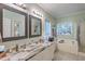 Elegant bathroom featuring a dual-sink marble vanity, framed mirrors, and a separate bathtub at 5950 Lowell Reed Rd, Ravenel, SC 29470
