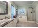 Bright bathroom featuring a soaking tub, glass-enclosed shower, and marble countertop vanity at 5950 Lowell Reed Rd, Ravenel, SC 29470