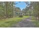 Charming traditional-style home with a welcoming front porch and a long gravel driveway, surrounded by lush trees at 5950 Lowell Reed Rd, Ravenel, SC 29470