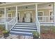 Close-up of the welcoming front porch with decorative plants and detailed trim at 5950 Lowell Reed Rd, Ravenel, SC 29470