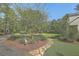 Landscaped front yard featuring a stone walkway, lush greenery, and mature trees on a spacious property at 5950 Lowell Reed Rd, Ravenel, SC 29470