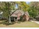Charming two-story brick home featuring a well-manicured lawn, mature trees, and welcoming front porch at 8781 Laurel Grove Ln, North Charleston, SC 29420