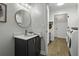 Modern bathroom with a round mirror, marble countertop, and wood-look floors at 99 Shadowmoss Pkwy, Charleston, SC 29414