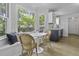 A dining area with a white table and wicker chairs nestled in a sunlit bay window next to the kitchen at 99 Shadowmoss Pkwy, Charleston, SC 29414