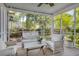 A screened porch with a seating area with white wicker furniture and a ladder with a blanket at 99 Shadowmoss Pkwy, Charleston, SC 29414