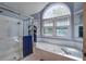Bright bathroom featuring a soaking tub, tiled shower, and large arched window for ample natural light at 101 N Warwick Trce, Goose Creek, SC 29445