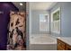 Stylish tub with a spooky shower curtain set between a window and a purple wall at 109 E Hartwick Ln, Goose Creek, SC 29445