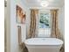 Elegant bathroom featuring a freestanding tub, patterned curtains, and a large window at 1106 Meadowcroft Ln, Mount Pleasant, SC 29464