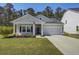 Charming single-story home with a manicured lawn, an attached garage, and an American flag on the front porch at 117 Camellia Bloom Dr, Moncks Corner, SC 29461