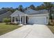 Inviting single-story home featuring a well-kept lawn, concrete driveway and covered porch with an attached two-car garage at 117 Camellia Bloom Dr, Moncks Corner, SC 29461