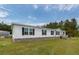 Angle view of a white manufactured home with black shutters and a spacious green lawn at 1330 Whitehouse Rd, Summerville, SC 29486