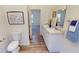 Bright bathroom features a double vanity with white cabinets and a framed floral print at 1576 Pine Grove Rd, Ruffin, SC 29475