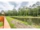 Picturesque pond surrounded by lush greenery, mature trees, and a wooden fence creating a serene backyard oasis at 158 Boots Branch Rd, Summerville, SC 29485