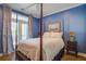 Comfortable bedroom with four-poster bed, blue walls, and access to private balcony at 1637 Folly Creek Way # E-12, Charleston, SC 29412