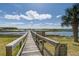 Picturesque view of a wooden dock extending into the water, surrounded by lush greenery and a blue sky at 1637 Folly Creek Way # E-12, Charleston, SC 29412