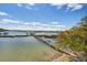 Aerial view of the serene waterfront featuring a wooden dock, set against a backdrop of clear blue skies at 1637 Folly Creek Way # E-12, Charleston, SC 29412