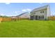 Spacious backyard with a large grassy area, wooden fence, screen porch, and play area at 1728 Refuge Dr, Ladson, SC 29456