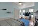 A serene bedroom with light blue walls, ceiling fan, and a clothing rack by the window at 197 Coming St, Charleston, SC 29403