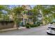 Charming two-story home with a light yellow exterior, teal shutters and door, and mature trees at 197 Coming St, Charleston, SC 29403