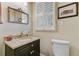 Charming powder room featuring granite countertops, dark wood cabinets, and window with plantation shutters at 207 Central Ave, Summerville, SC 29483