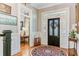 Inviting foyer with hardwood floors, stylish rug, and decorative black front door at 207 Central Ave, Summerville, SC 29483