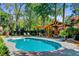 An in-ground pool with a covered patio and lounge chairs, surrounded by lush trees at 207 Central Ave, Summerville, SC 29483