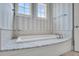 Bright bathroom featuring a large soaking tub with marble surround, stylish tile accents, and ample natural light at 21 Morgan Place Dr, Isle of Palms, SC 29451