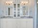 Elegant bathroom features a double vanity with marble countertops, decorative lighting, and a linen cabinet at 21 Morgan Place Dr, Isle of Palms, SC 29451