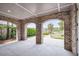 Covered patio with brick arches framing a view of the landscaped backyard and waterway at 21 Morgan Place Dr, Isle of Palms, SC 29451