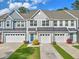 Exterior view of townhomes with well-manicured lawns and one car garages in a residential neighborhood at 210 Grand Palm Ln, Summerville, SC 29485