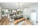 Bright dining room with a glass table, wood bench seating, modern chandelier, and an open concept view of the kitchen at 2668 Private Lefler Dr, Johns Island, SC 29455