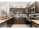 Well-equipped kitchen with dark wood cabinets, granite countertops, a decorative backsplash, and modern appliances at 3133 Cold Harbor Way, Charleston, SC 29414